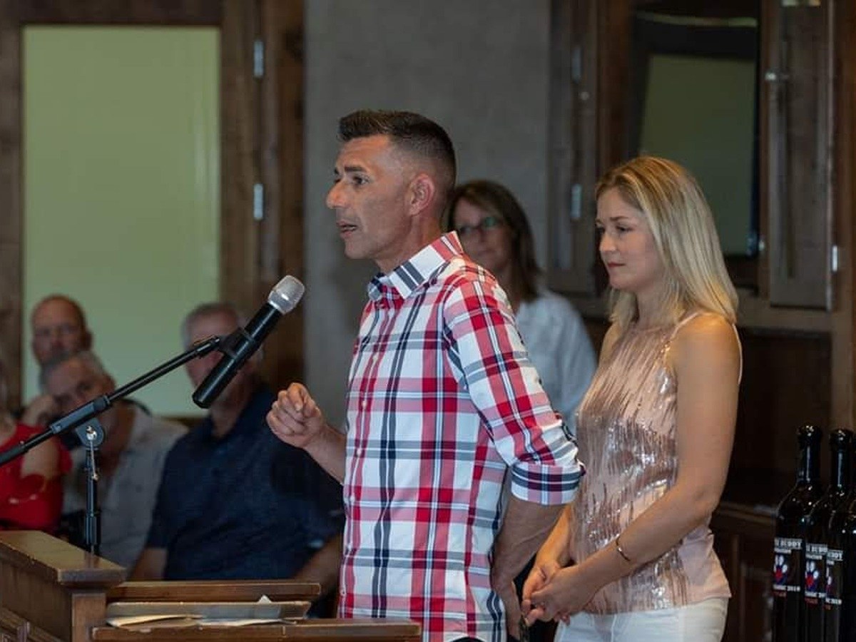 Kenny Bass speaking at a microphone at a community event.